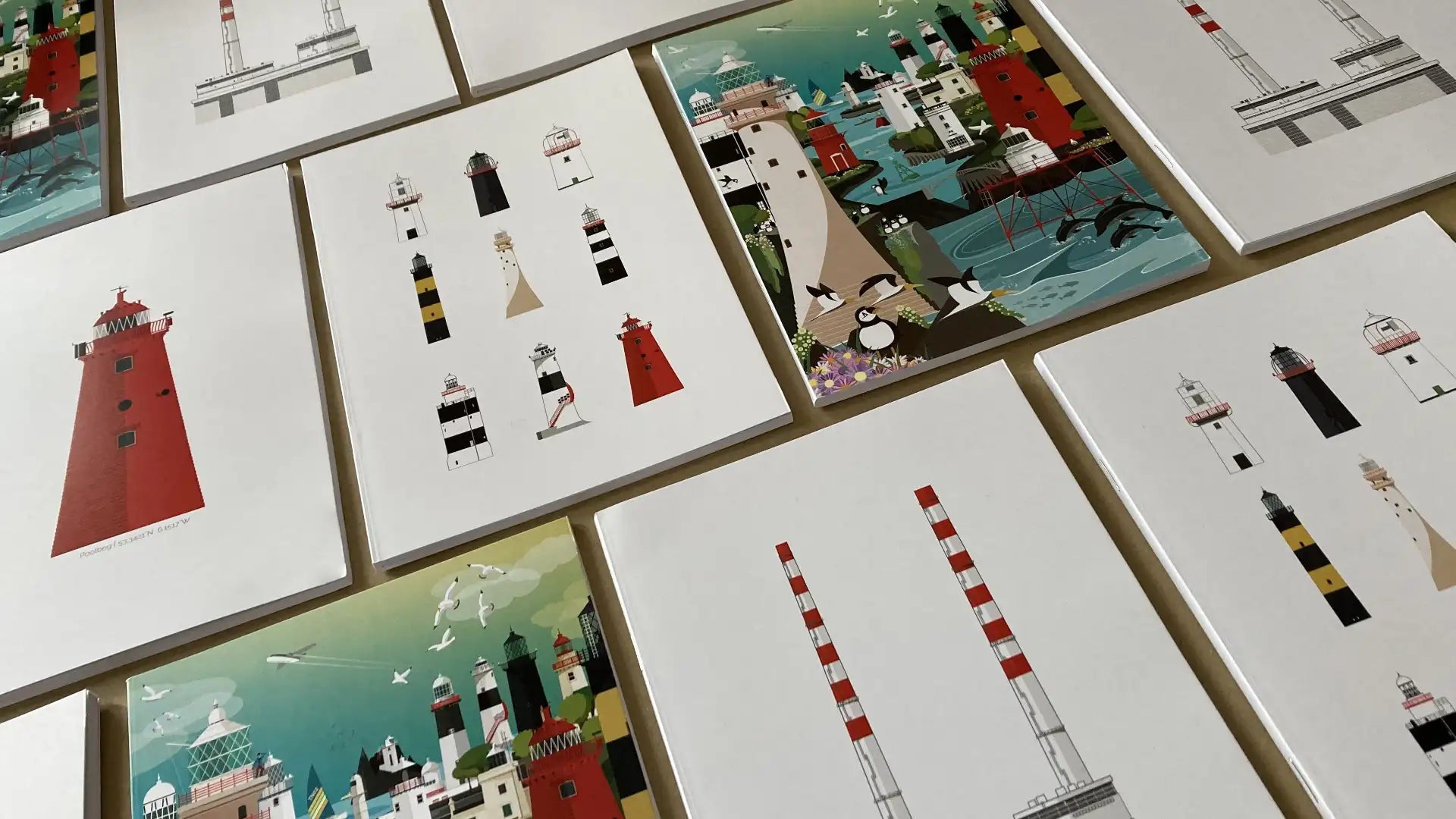 A selction of notebooks displaying their covers featuring lighthouses of ireland and the poolbeg chimneys.